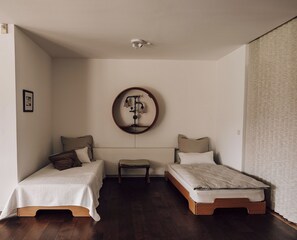 Un dormitorio pequeño y bien iluminado con dos camas individuales, una mesita y una lámpara fijada a la pared.
