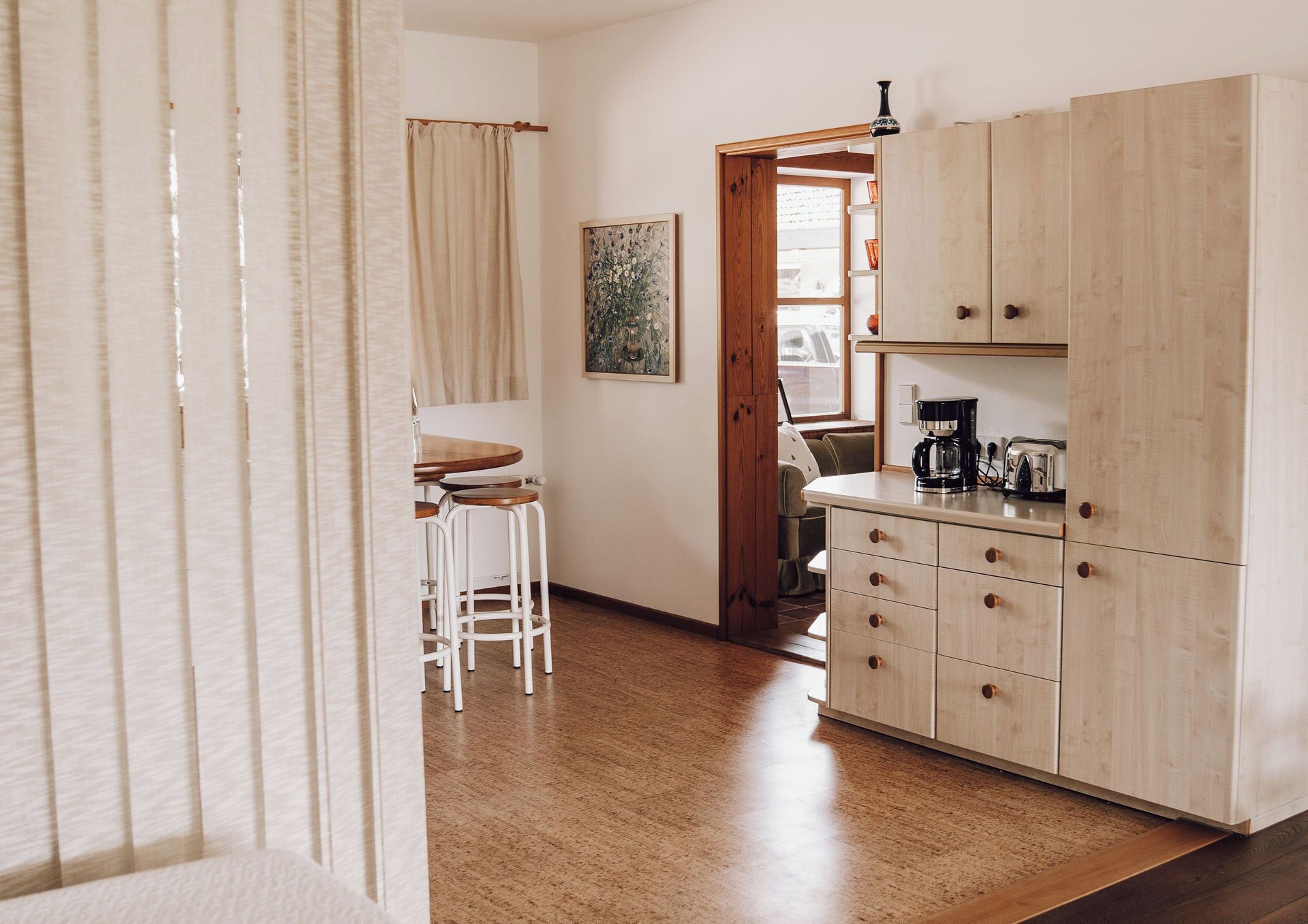 A kitchen with wooden cabinets, a coffee maker, and a toaster. There is a dining area with a table and chairs.
