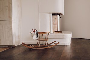 A wooden rocking chair in a modern room with a white bench and a fireplace.