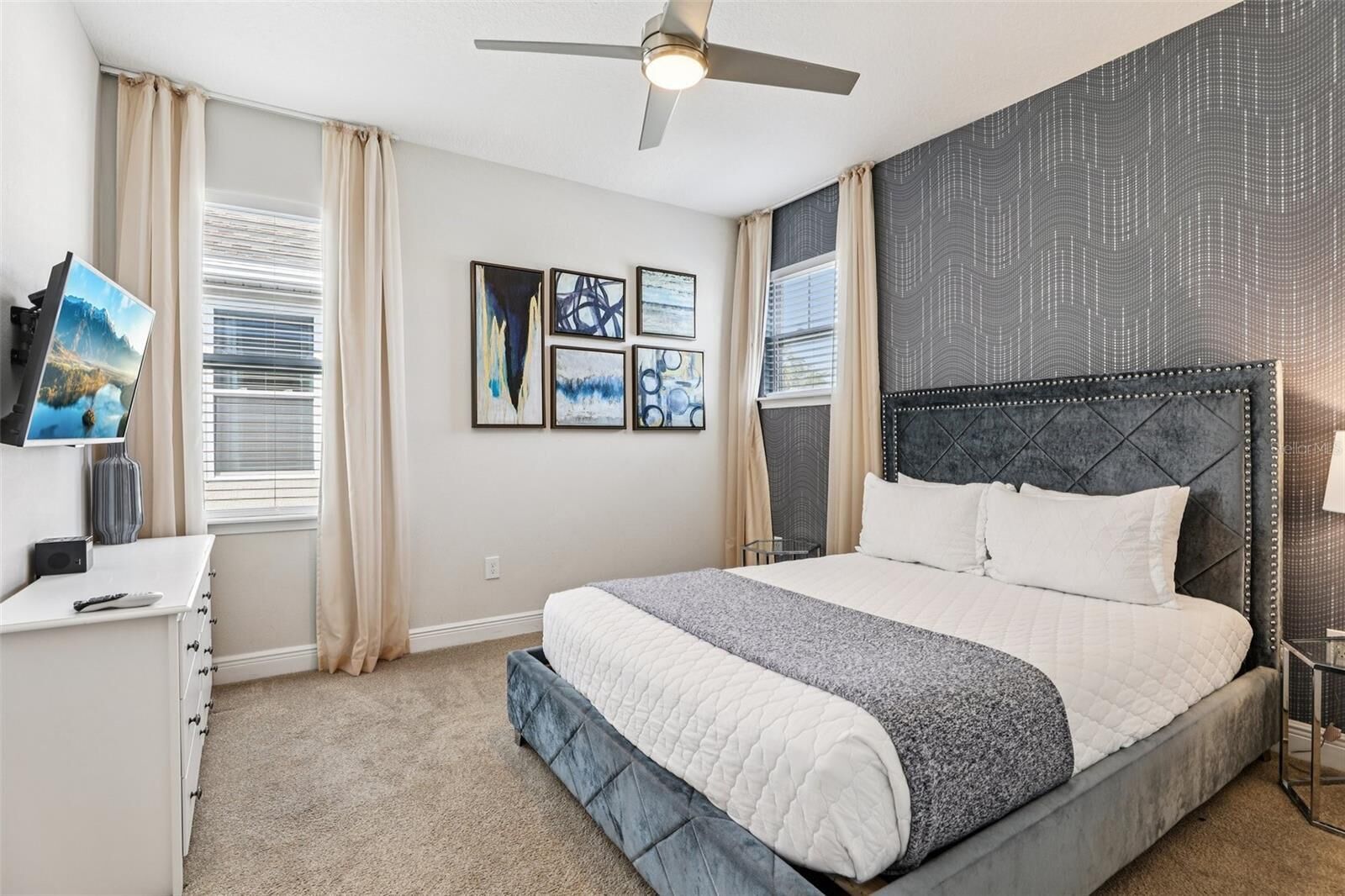 Ein Schlafzimmer mit Bett, Fernseher, Schreibtisch und Bildern an der Wand.