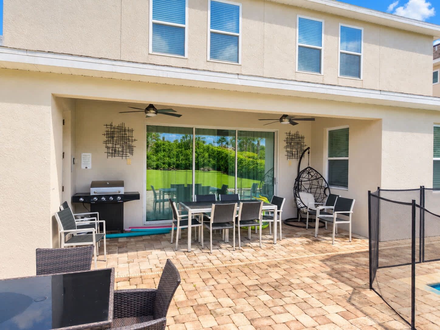 An outdoor patio with a grill, dining chairs, and a ceiling fan.