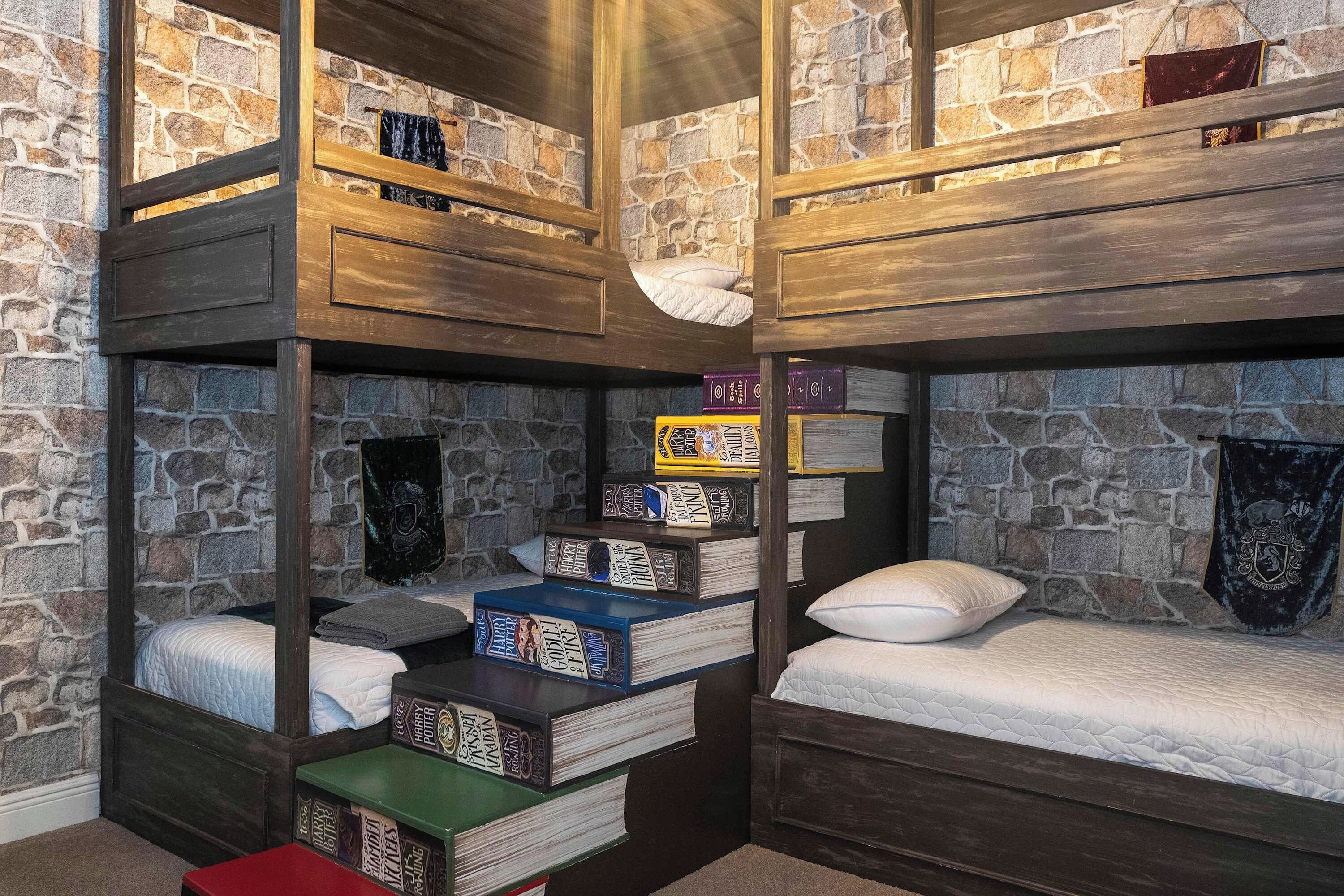 A multi-level bunk bed room with stone walls, wooden shelves, and a variety of books.
