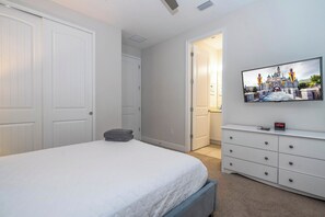 A bedroom with a bed, a dresser, a TV, and a door leading to another room. - Pool, Spa & Game Room Home for 12 at Encore (Kissimmee)