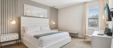 Un dormitorio moderno con cama, mesitas de noche, escritorio y ventilador de techo.