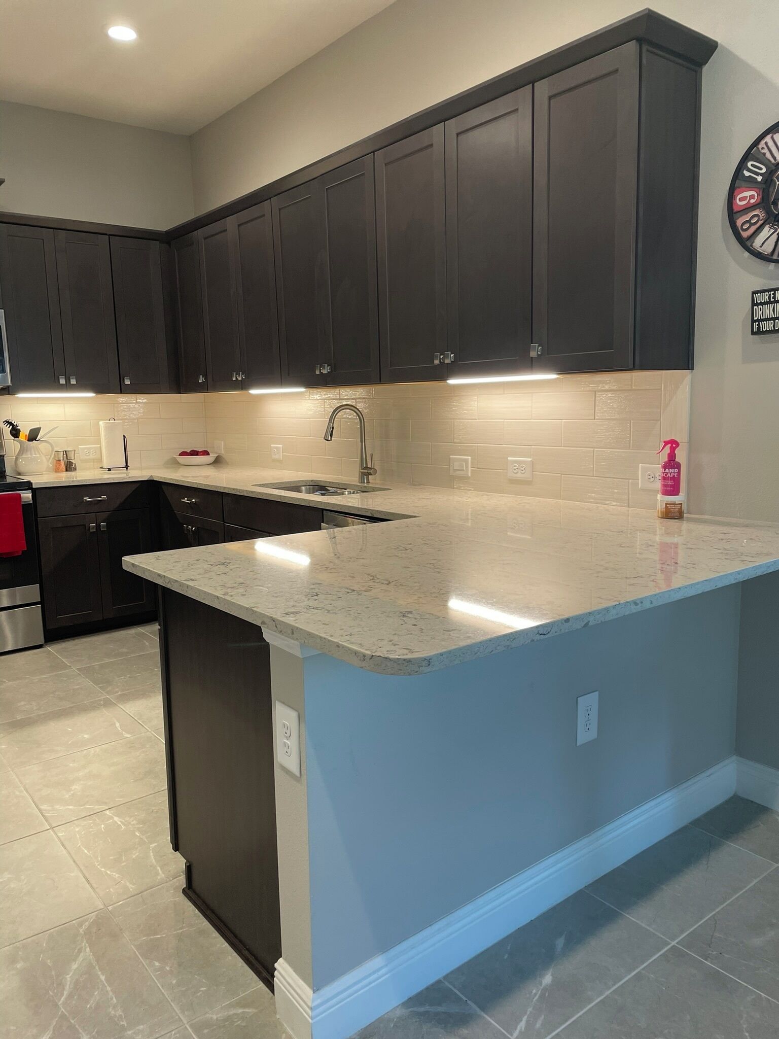 A kitchen with dark cabinets, a marble countertop, and a built-in island.