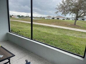 A room with a large window overlooking a grassy area with houses and a tree. - Golf Course-Pond, 2 Bed/2 Bath+ Den 2022 Villa-Quiet Active 55+ Gated Community (Port Charlotte)