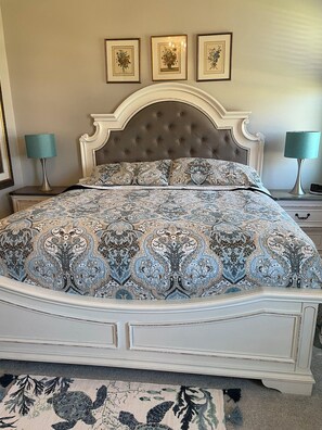 A bed with a patterned bedspread, a tufted headboard, and a nightstand with a lamp. - Golf Course-Pond, 2 Bed/2 Bath+ Den 2022 Villa-Quiet Active 55+ Gated Community (Port Charlotte)