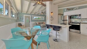 A spacious kitchen with modern appliances, a dining area with a glass table and turquoise chairs, and a ceiling fan. - 2 bedroom bungalow within walking distance to Siesta Village (Sarasota)