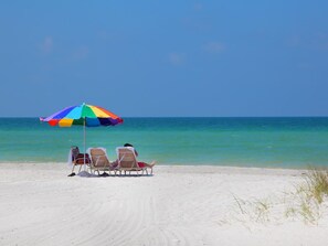 A beach with a colorful umbrella and two lounge chairs facing the ocean. - 2 bedroom bungalow within walking distance to Siesta Village (Sarasota)