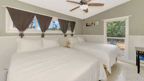 A bedroom with two beds, a ceiling fan, and a window with curtains. - 2 bedroom bungalow within walking distance to Siesta Village (Sarasota)