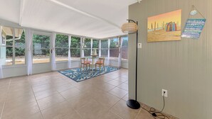 A spacious room with large windows, a dining area with chairs and a table, a patterned rug, and artwork on the wall. - 2 bedroom bungalow within walking distance to Siesta Village (Sarasota)