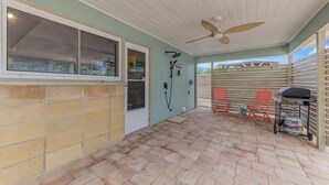 A covered patio area with a ceiling fan, a barbecue grill, and two red chairs. - 2 bedroom bungalow within walking distance to Siesta Village (Sarasota)