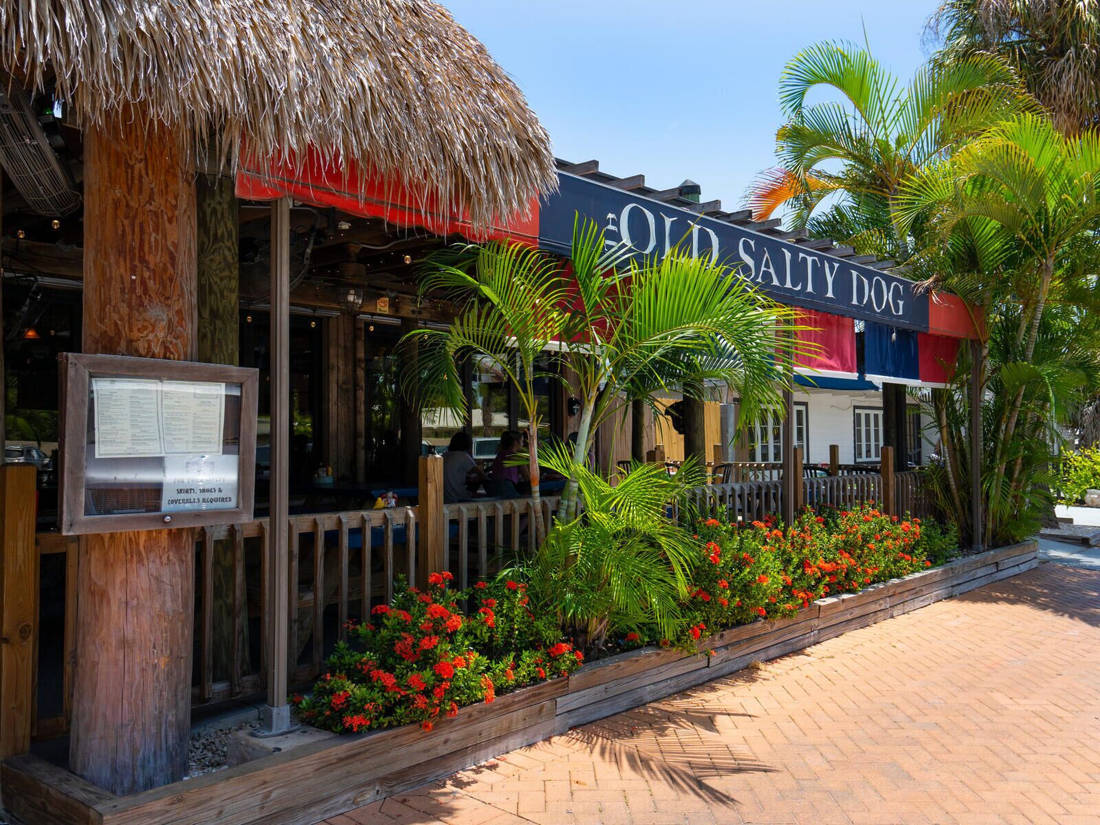 A restaurant named "Old Salty Dog" with a thatched roof, wooden columns, and a wooden fence.