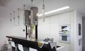 A modern kitchen with a central island, pendant lights, and built-in appliances.