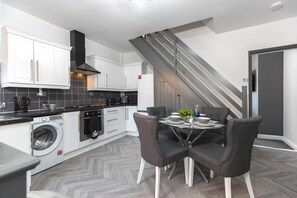 Een moderne keuken met witte kastjes, een ingebouwde oven en een wasmachine.
