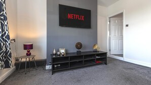 A modern living room with a flat-screen TV mounted on the wall, a black entertainment unit below, and a door to the right. - The Waltons – Ideal Durham Escape - Nature Lovers - Pass the Keys (New Brancepeth)