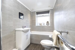 Une salle de bain moderne équipée de toilettes, d’un lavabo et d’une baignoire.