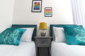 Une chambre d’hôtel avec deux lits, une table de chevet avec une lampe et deux tableaux encadrés au mur.