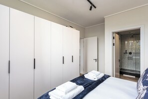 Ein Schlafzimmer mit einem Bett, zwei Kleiderschränken und einem Duschbereich.
