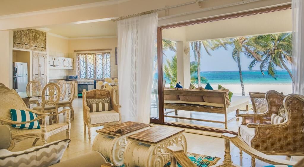 Amplia sala de estar con vista a la playa, una mesa de comedor y muebles de mimbre.