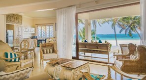 Un vaste espace de vie avec vue sur la plage, une table à manger et des meubles en osier.