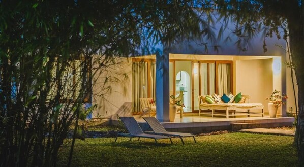 A modern house with a patio, a sofa, and two lounge chairs.