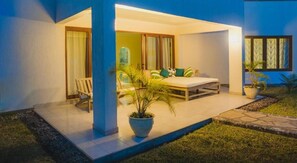 Un espace extérieur moderne aménagé avec une table et des chaises, un pot de fleurs et une porte vitrée donnant sur une pièce.