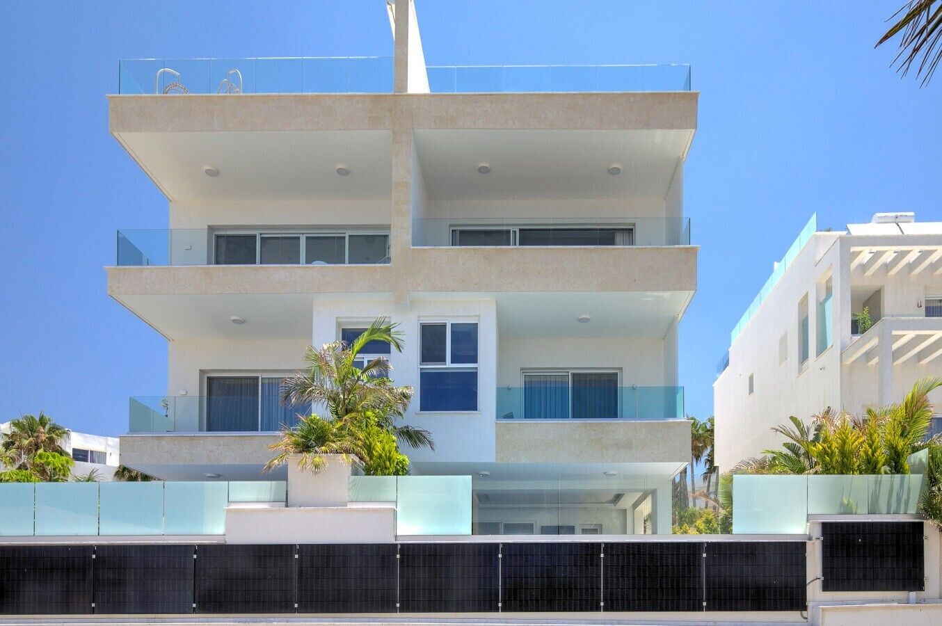 A multi-story building with balconies, large windows, and a clear sky.