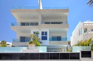 Un edificio de varios pisos con balcones, ventanas grandes y cielo despejado.