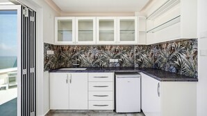 Uma cozinha moderna com armários brancos, painel de azulejos e máquina de lavar louça embutida.