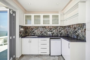 A modern kitchen with white cabinetry, a tiled backsplash, and a built-in dishwasher. - Olymp Royal Palace - Ultra Luxury Beachfront House (Paphos)