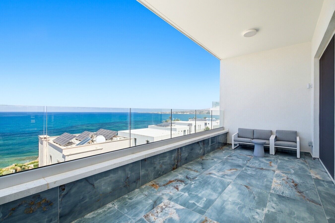 Un balcón con vistas al mar, zona de estar y diseño arquitectónico moderno.