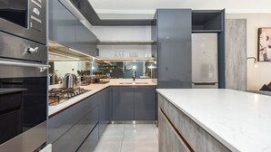 A modern kitchen with a central island, built-in appliances, and a large window. - The Paramount | Contemporary Luxury (Johannesburg)