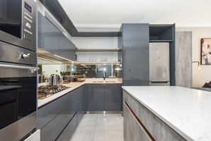 A modern kitchen with a central island, built-in appliances, and a large window. - The Paramount | Contemporary Luxury (Johannesburg)