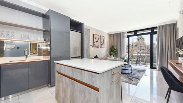 A modern kitchen with a central island, a built-in oven, and a dining area with a view. - The Paramount | Contemporary Luxury (Johannesburg)