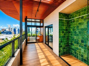 A modern balcony with a wooden floor, glass doors, and a view of the cityscape. - Breeze Residence 317 Beachfront Apartment in Bessa (João Pessoa)