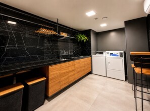 Eine moderne Küche mit schwarzem Marmor-Arbeitsplatz, Holzschränken und einer integrierten Waschmaschine.