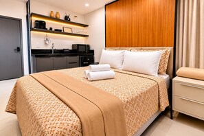 A hotel room with a bed, a desk, a microwave, and a coffee machine. - Breeze Residence 317 Beachfront Flat at Bessa (João Pessoa)