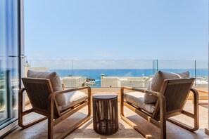 Un balcón con dos sillas y una mesita pequeña, con vista al mar.