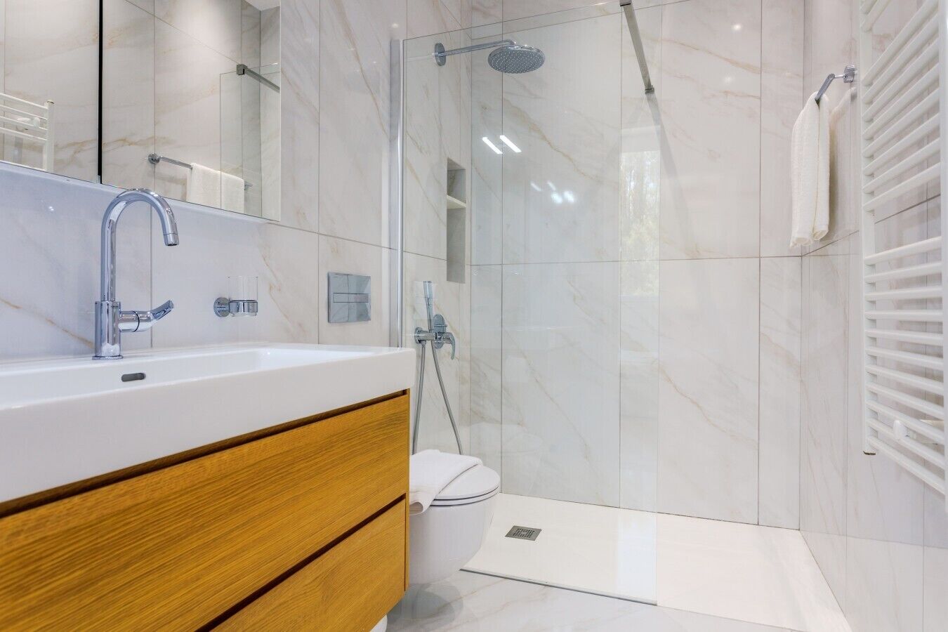 A modern bathroom with a glass-enclosed shower, a white sink, and a wooden vanity.