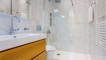 A modern bathroom with a glass-enclosed shower, a white sink, and a wooden vanity.