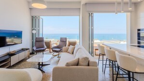Una sala de estar moderna con un televisor de pantalla plana grande, asientos cómodos y vistas al océano.