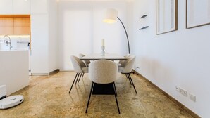 Un comedor moderno con una mesa y sillas, una lámpara colgante y una cocina visible al fondo.