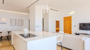 Un espacio habitable moderno con una isla central, un sofá, un televisor y una zona de comedor.