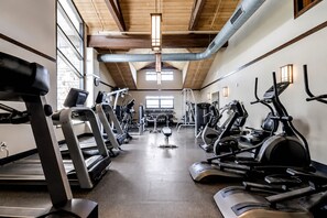 Un gimnasio con cintas de correr, elípticas y máquinas de pesas.