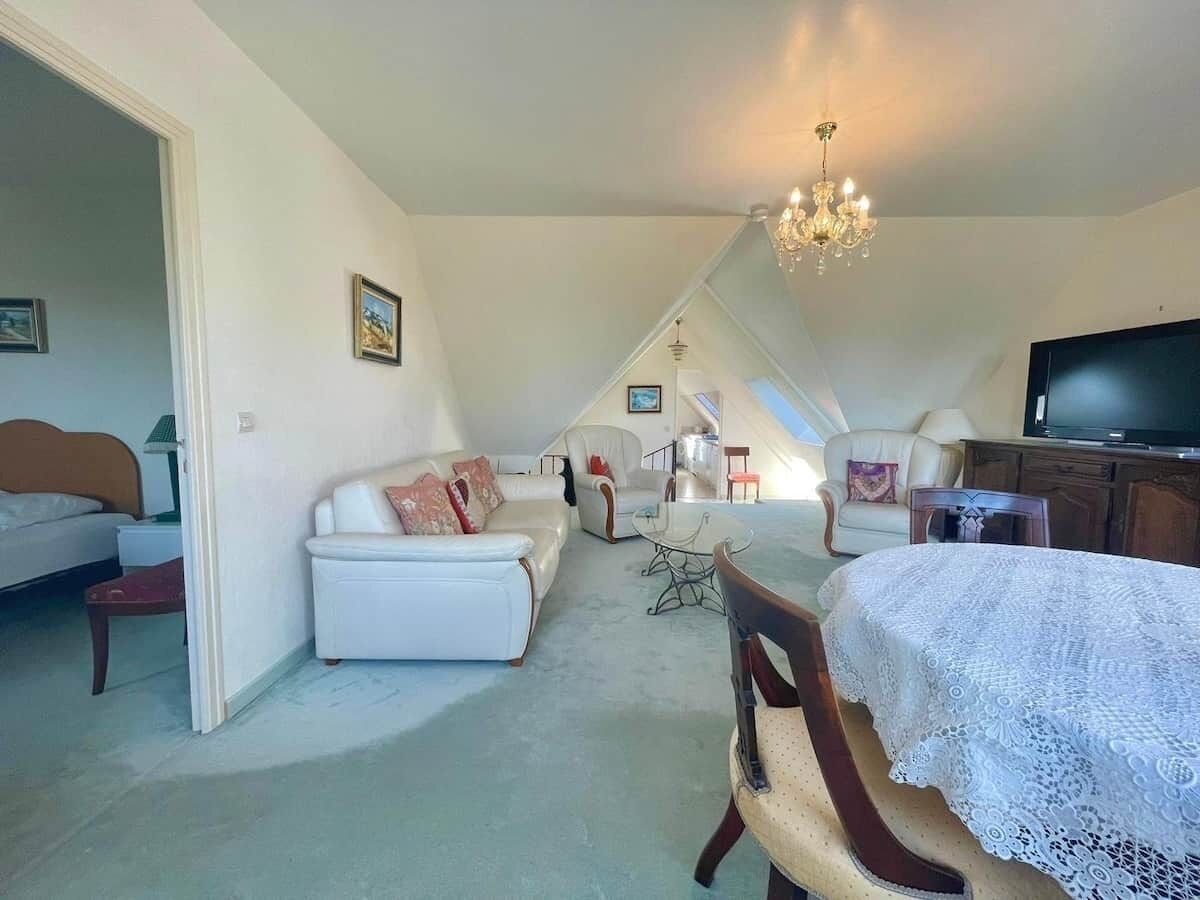 Une chambre spacieuse située dans les combles, avec un grand lit, une table à manger et un téléviseur.