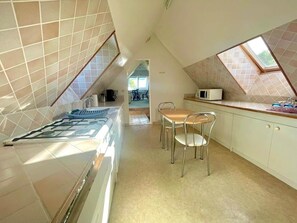 Een keuken met een eethoek, een magnetron en uitzicht door een dakraam.
