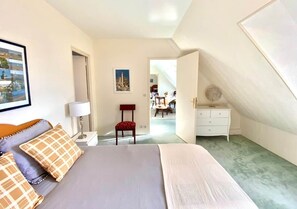 A bedroom with a bed, a chair, a dresser, and a painting on the wall.