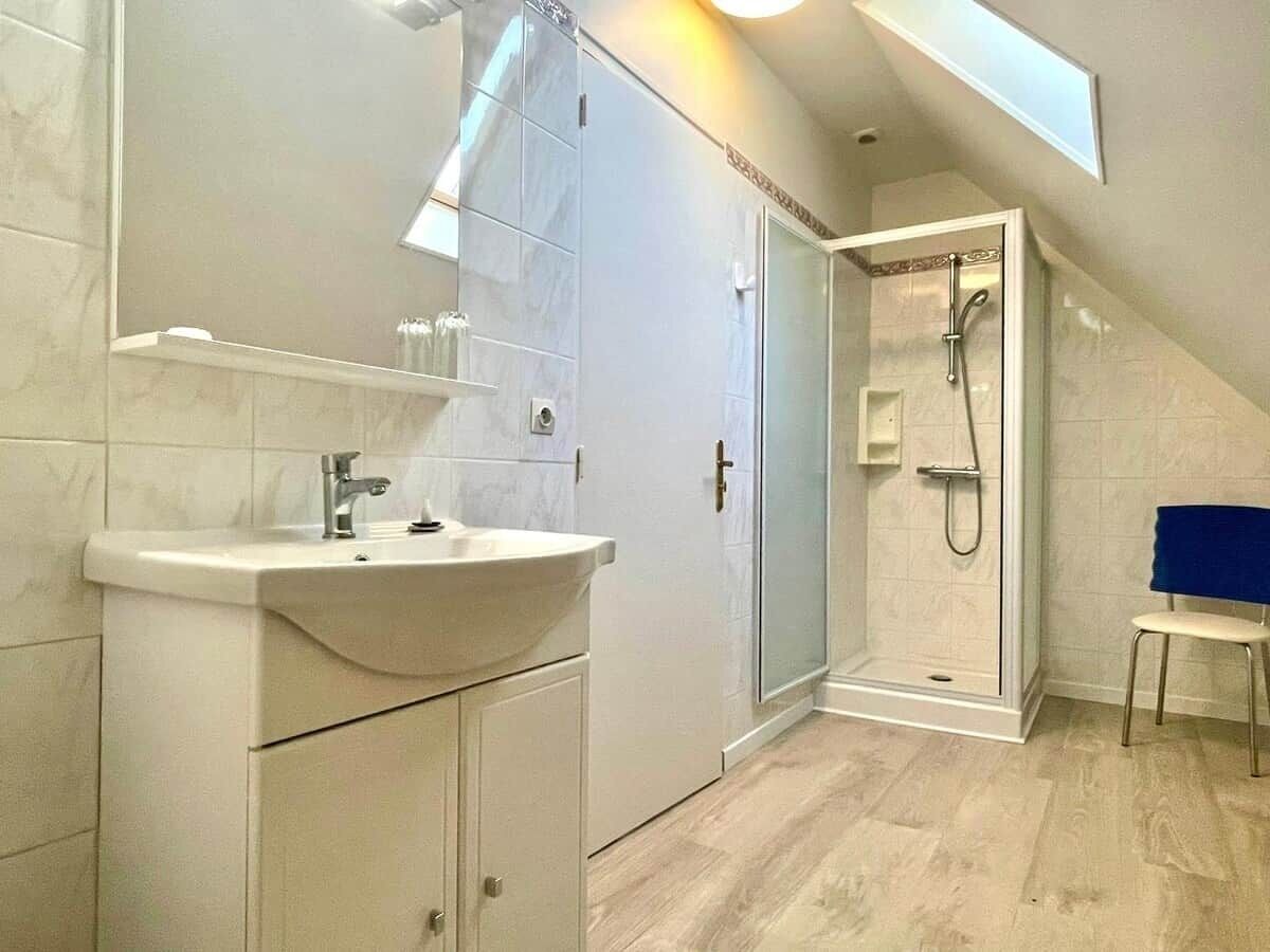 Ein modernes Badezimmer mit Dusche, Waschbecken und einem Sessel.