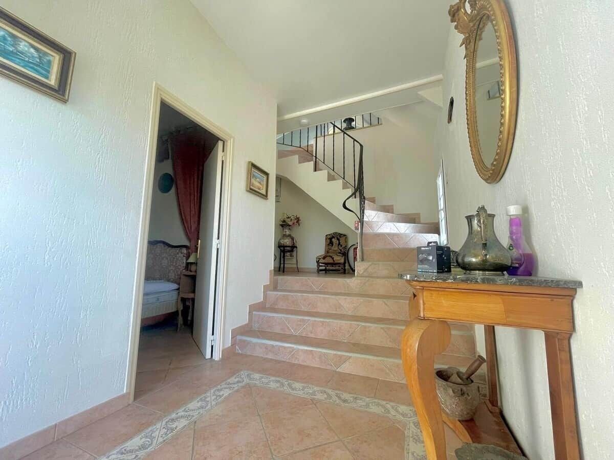 Un escalier menant à une chambre à coucher équipée d’un lit, d’une table de chevet et d’une commode.